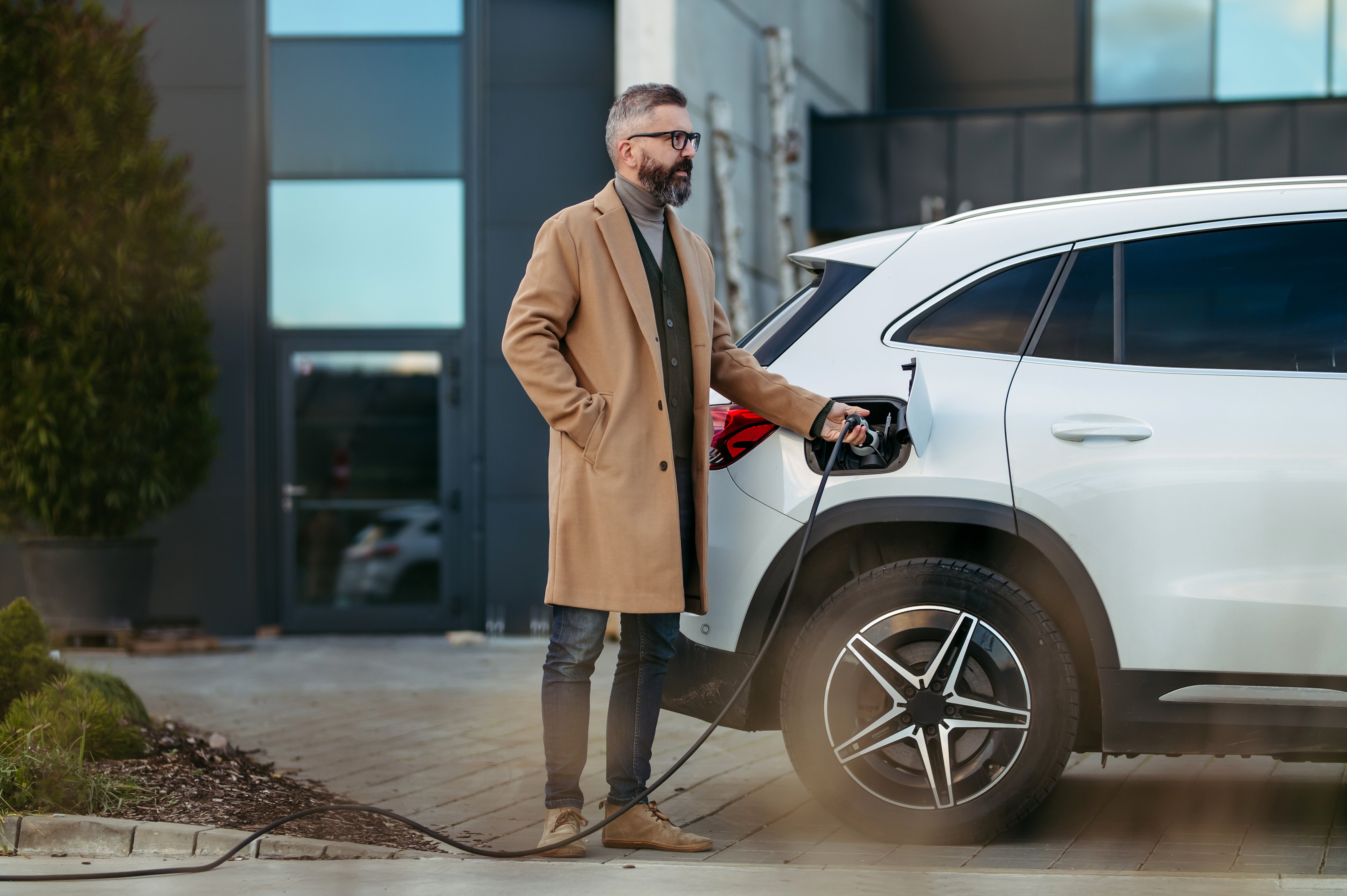 A man using a workplace EV charging station for cars.
