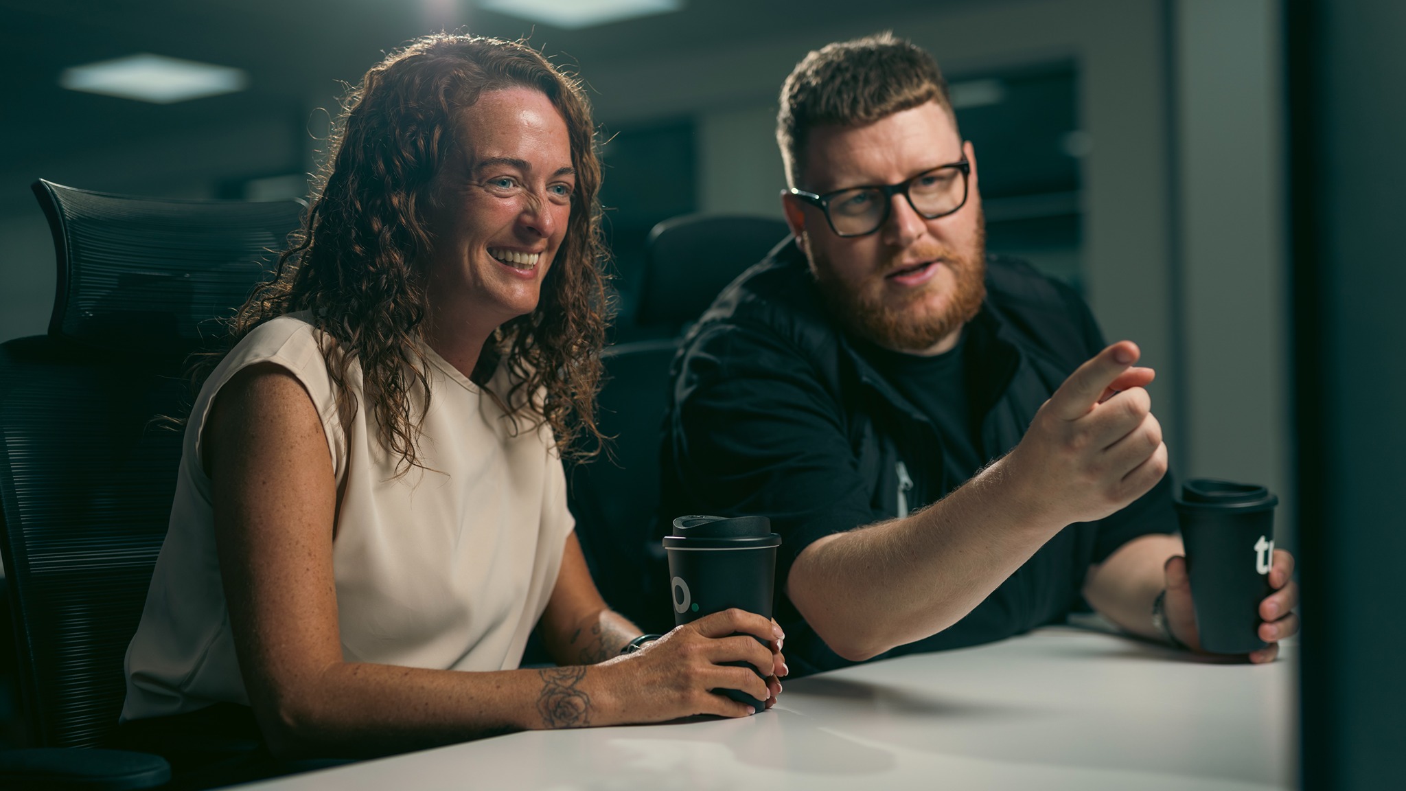 A woman and man discuss business gas contracts while pointing at a screen.