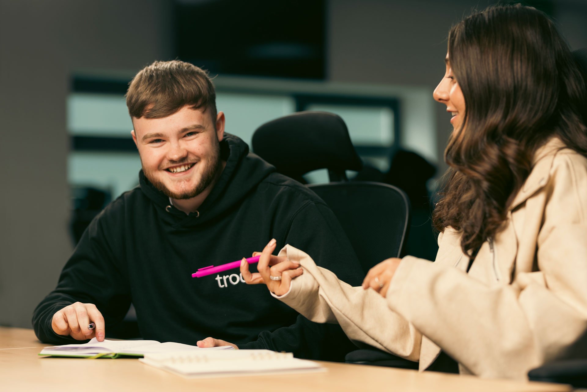 Two people smiling while having a conversation in the Troo office