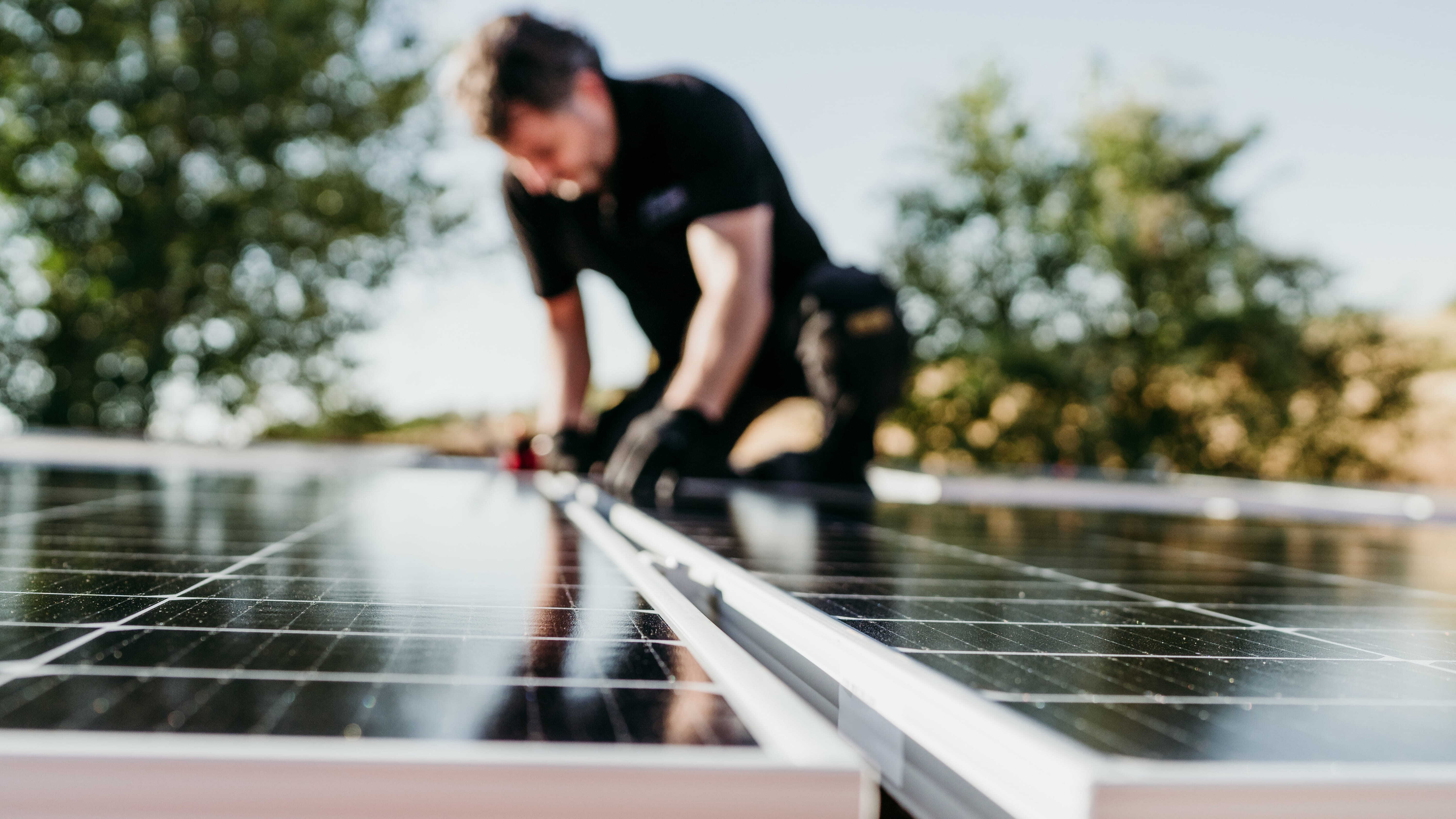 A man fits a solar panel to a roof