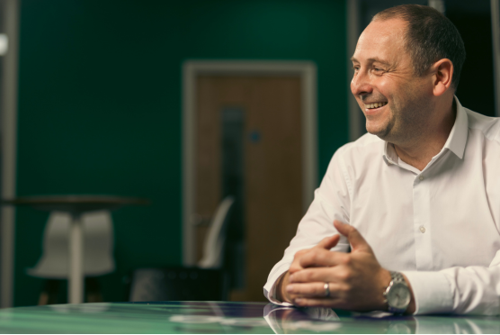Close up shot of man at office desk, smiling